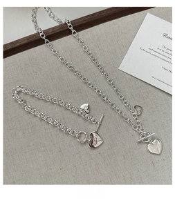 Détail du fermoir OT argenté sur l'ensemble collier et bracelet cœur avec gravure Lucky