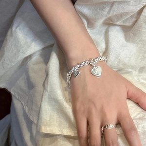 Gros plan de pendentifs cœur argentés avec gravure Lucky sur un bracelet à grosse chaîne