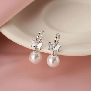 Elegant bow shell pearl drop earrings for women in S925 silver on white ceramic plate