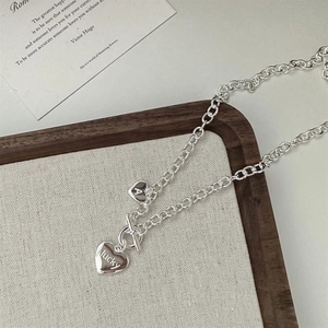 Détail du collier à fermoir OT argenté avec doubles pendentifs cœur et gravure lucky
