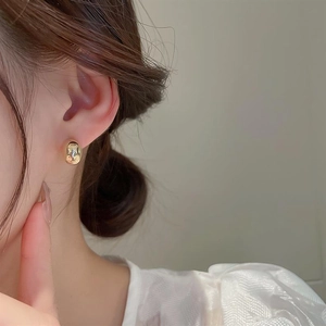 Close-up of model wearing golden irregular bean stud earrings with hammer texture