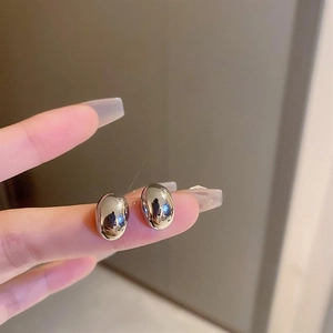 Close-up of polished silver bean-shaped stud earrings with reflective mirror finish