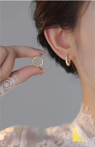 Detailed view of twisted rope texture on gold hoop earrings for a stylish look