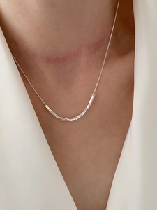 Close-up of minimalist S925 sterling silver necklace featuring small geometric square charms