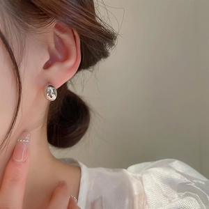 Polished silver bean stud earring shown on model with minimalist high-gloss finish