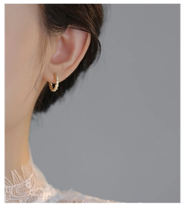 Close-up of golden twisted rope hoop earrings on ear for an elegant minimalist look