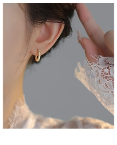 Close-up of twisted gold hoop earrings showing metallic spiral texture on female model