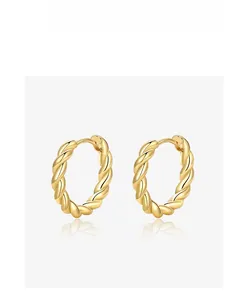 Detail of gold twisted rope hoop earrings with shiny metallic reflection and textured finish