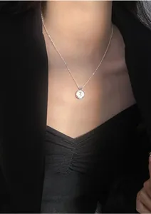 Detailed close-up of a sterling silver rose flower stamp pendant on a thin rope chain necklace