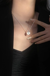 Close-up of a silver rose medallion necklace worn on a model with an elegant look