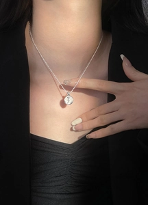 Detail of S925 sterling silver water wave chain with a vintage rose coin pendant on neck