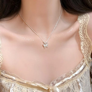 Gros plan du pendentif papillon œil-de-chat élégant porté au cou pour un look raffiné