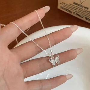 Détail du collier pendentif papillon avec incrustation d'opale et bordure perlée