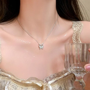 Gros plan du collier avec pendentif papillon en opale œil-de-chat porté par un modèle