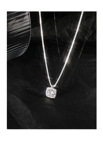 Detailed close-up of a silver square zircon pendant on a delicate box chain necklace