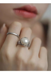 Detailed macro of vintage silver hollowed ring with a lustrous white pearl on model