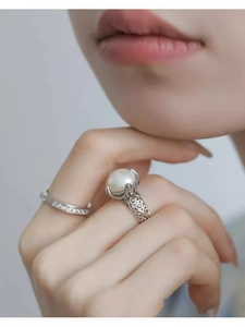 Detail of S925 silver pearl ring with vintage hollow pattern and diamond band on finger