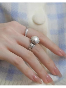 Detail of vintage hollow silver ring featuring a large round pearl on model hand