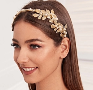 Detailed view of bridal golden leaf headband with pearls worn on a female model