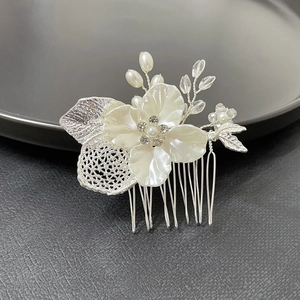 Close-up of bridal hair comb with white flowers, pearls, and silver leaves details