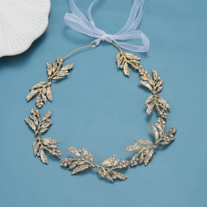 Dettagli della fascia da sposa dorata con foglie di strass e un nastro in chiffon leggero
