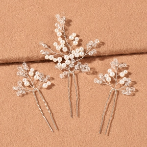 Detail of three bridal hair pins with white pearls and silver crystal branches on fabric