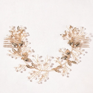 Close-up of golden leaf bridal hair comb with elegant white pearls and wire mesh