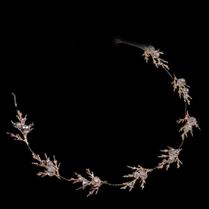 Détail d'un accessoire de coiffure de mariée avec feuilles dorées et cristaux brillants