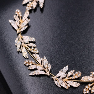 Dettaglio macro di fascia per capelli con foglie dorate e strass per acconciatura sposa