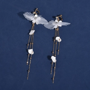 Détail de boucles d'oreilles papillon en tulle blanc avec pompons dorés et cristaux