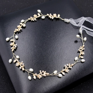 Elegant gold bridal headband with white pearls, crystals, and flowers on black backdrop