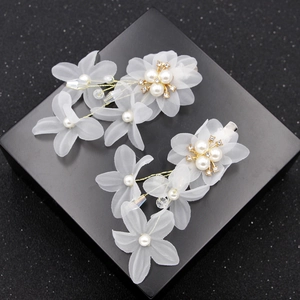 Elegant white floral bridal hair clips with pearls and crystals on a black display box