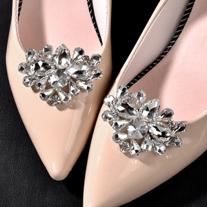 Gros plan de boucles en cristal étincelant sur des escarpins de mariée en cuir verni beige