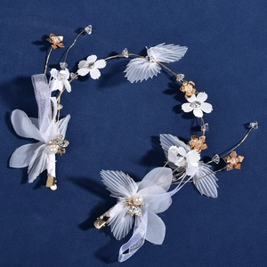 Détail de serre-tête de mariée avec fleurs en tissu blanc et perles sur fond bleu