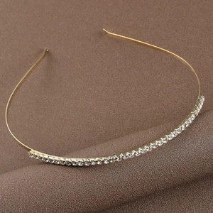 Close-up detail of a minimalist gold alloy bridal headband with sparkling rhinestones