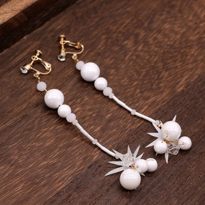 Vue détaillée de longues boucles d'oreilles perles blanches avec étoiles dorées sur bois