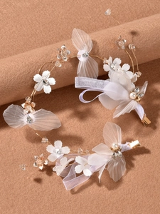 Détail de coiffe de mariée avec nœuds en résille, fleurs en tissu, perles et cristaux
