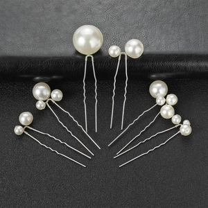 Détail de sept épingles à cheveux de mariée avec perles blanches sur fond en cuir noir