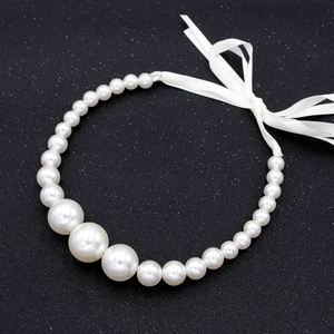 Élégant collier de perles dégradées avec rubans de satin blanc sur fond noir brillant