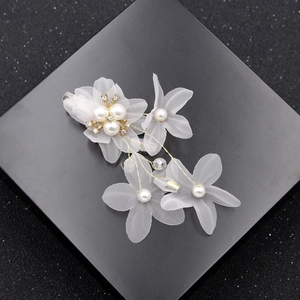 Detail of white organza flower hair clip with pearls, rhinestones and golden wire accents