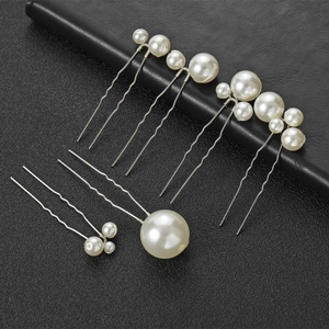 Détail de six épingles à cheveux en perles blanches de tailles variées sur fond cuir