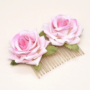 Detailed close-up of double pink velvet roses with green leaves on a gold metal hair comb