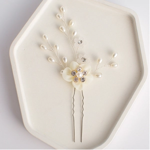 Ivory bridal hair comb with fabric flowers and pearls on white hexagonal display tray
