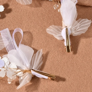 Détail de deux barrettes fleurs en organza blanc avec pinces crocodiles en métal doré
