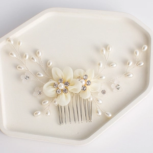 Detailed macro view of ivory fabric flowers and pearls on a bridal hair comb