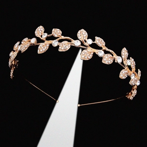 Golden bridal crown with rhinestone leaves on black background with lighting