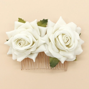 Detail view of white velvet rose bridal hair comb with gold metal teeth and green leaves