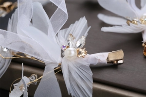 Gros plan sur pince à cheveux mariée avec pétales de mousseline, perles et strass papillon