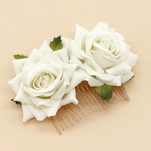 Elegant bridal hair comb with dual white velvet roses and golden metal teeth on beige surface
