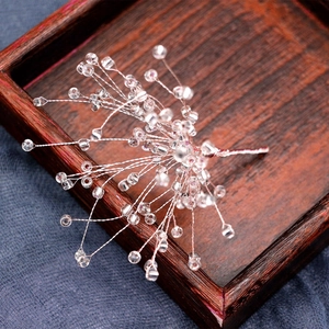 Handmade bridal hair clip with white beaded snowflakes on elegant dark wooden background